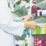 Apotheker mit Medikamenten in der Hand vor Regal Case Study