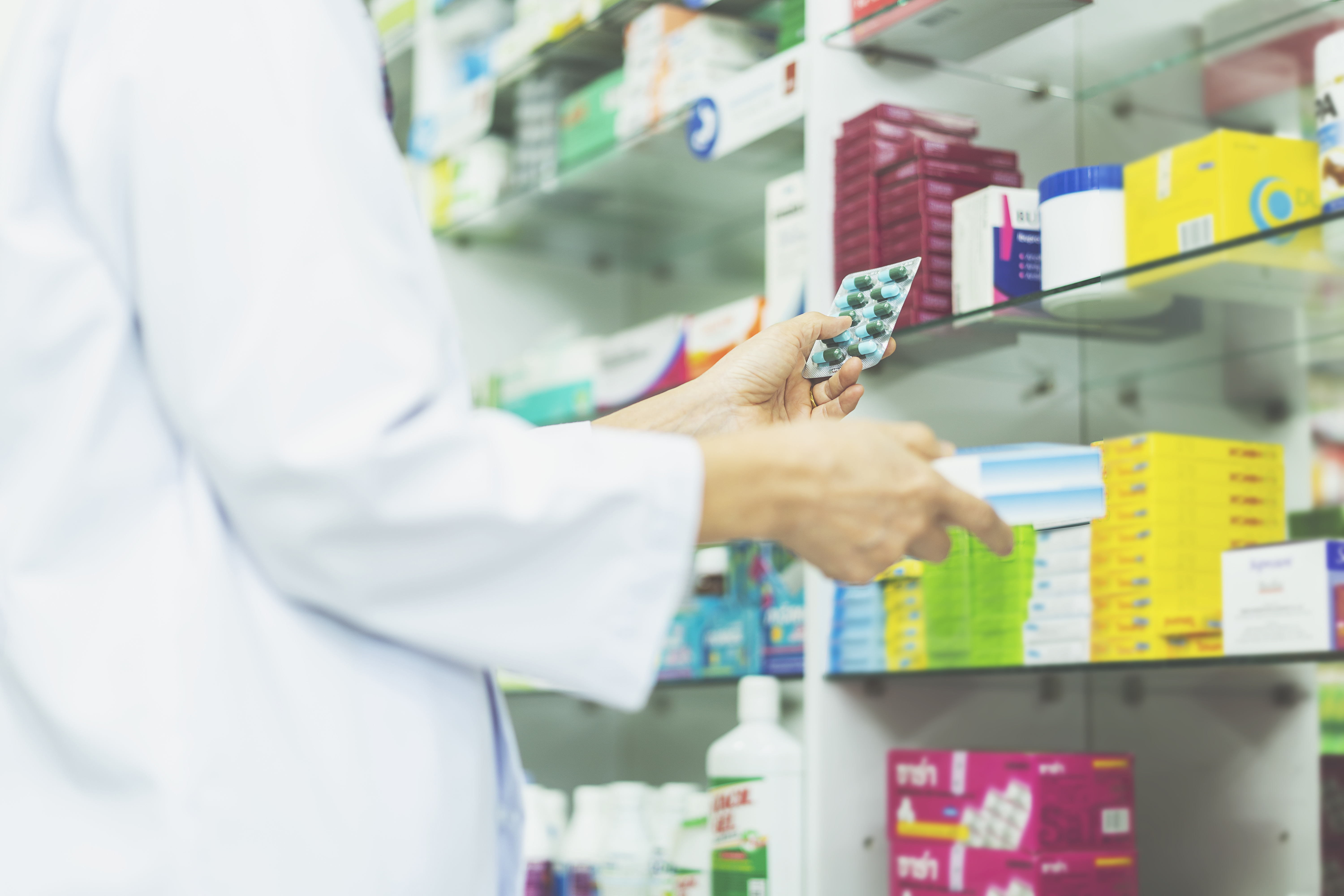 Apotheker mit Medikamenten in der Hand vor Regal Case Study