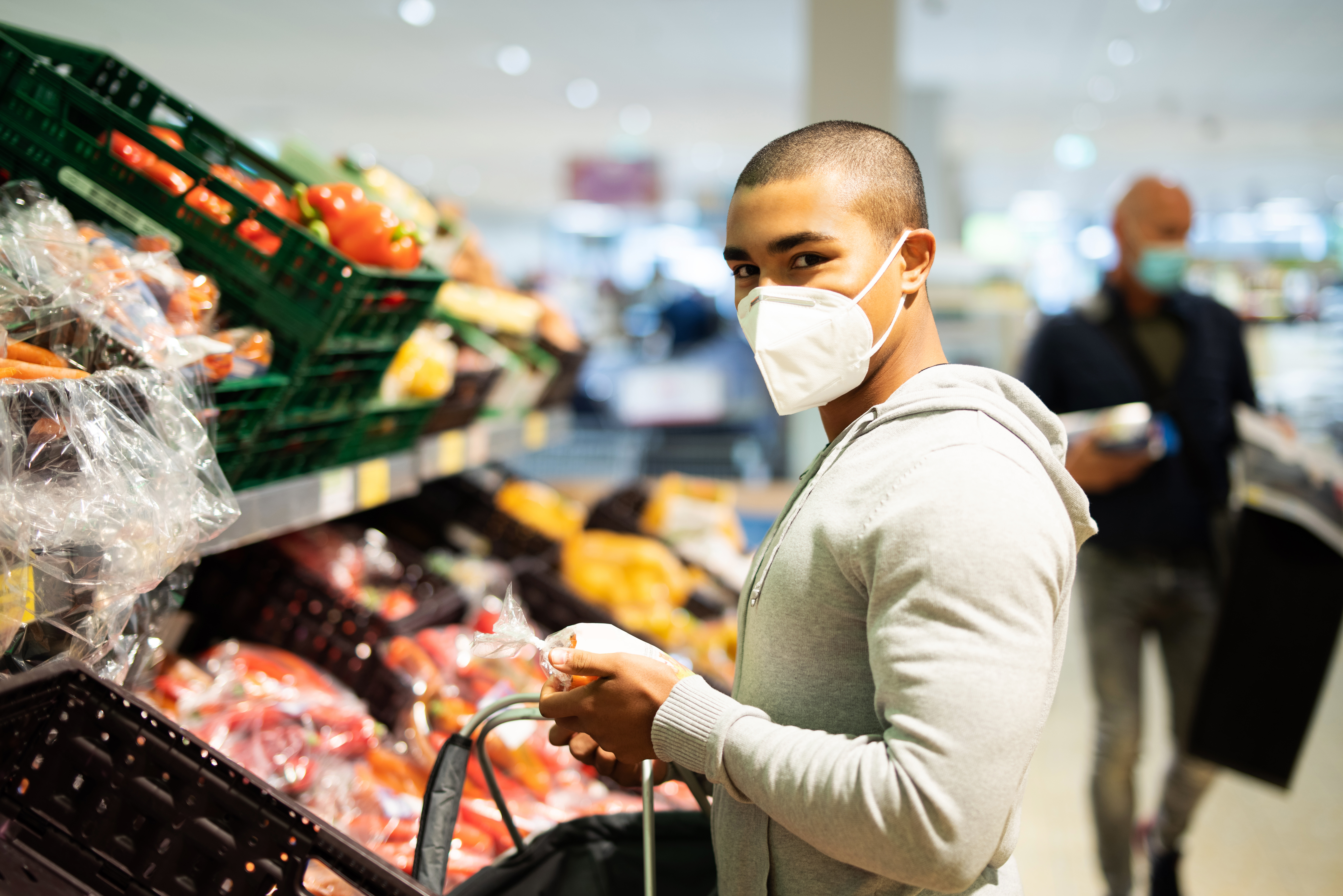 Einkaufen zur Zeit des Coronavirus, Mann mit Atemmaske in Supermarkt