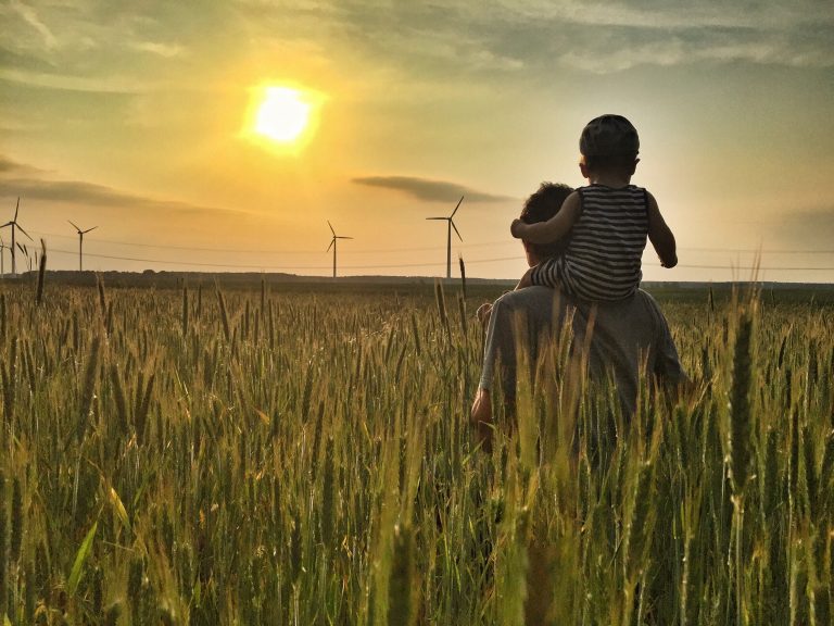 Windräder Sonnenuntergang Mann mit Kind auf Schultern im grünen Kornfeld