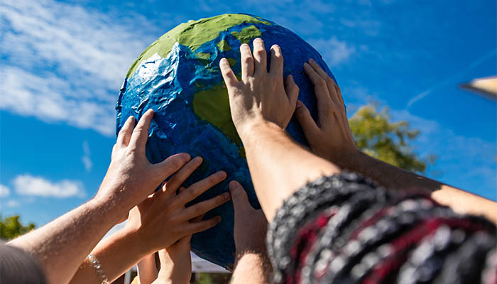 Many hands holding a giant terrestrial globe