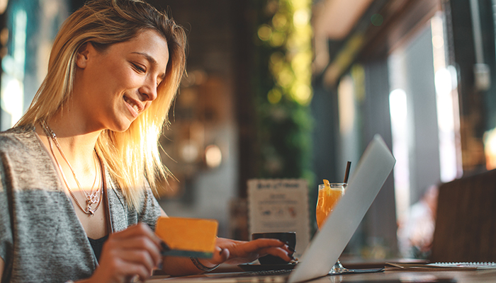Junge Frau mit Kreditkarte beim Online-Einkauf in einem Café