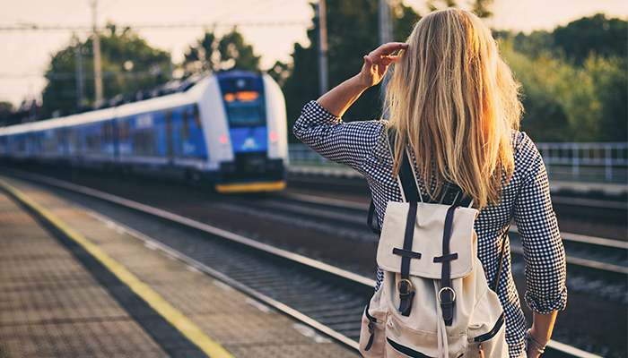 Deutschland Ticket Frau mit Rucksack steht am Gleis und schaut S-Bahn hinterher