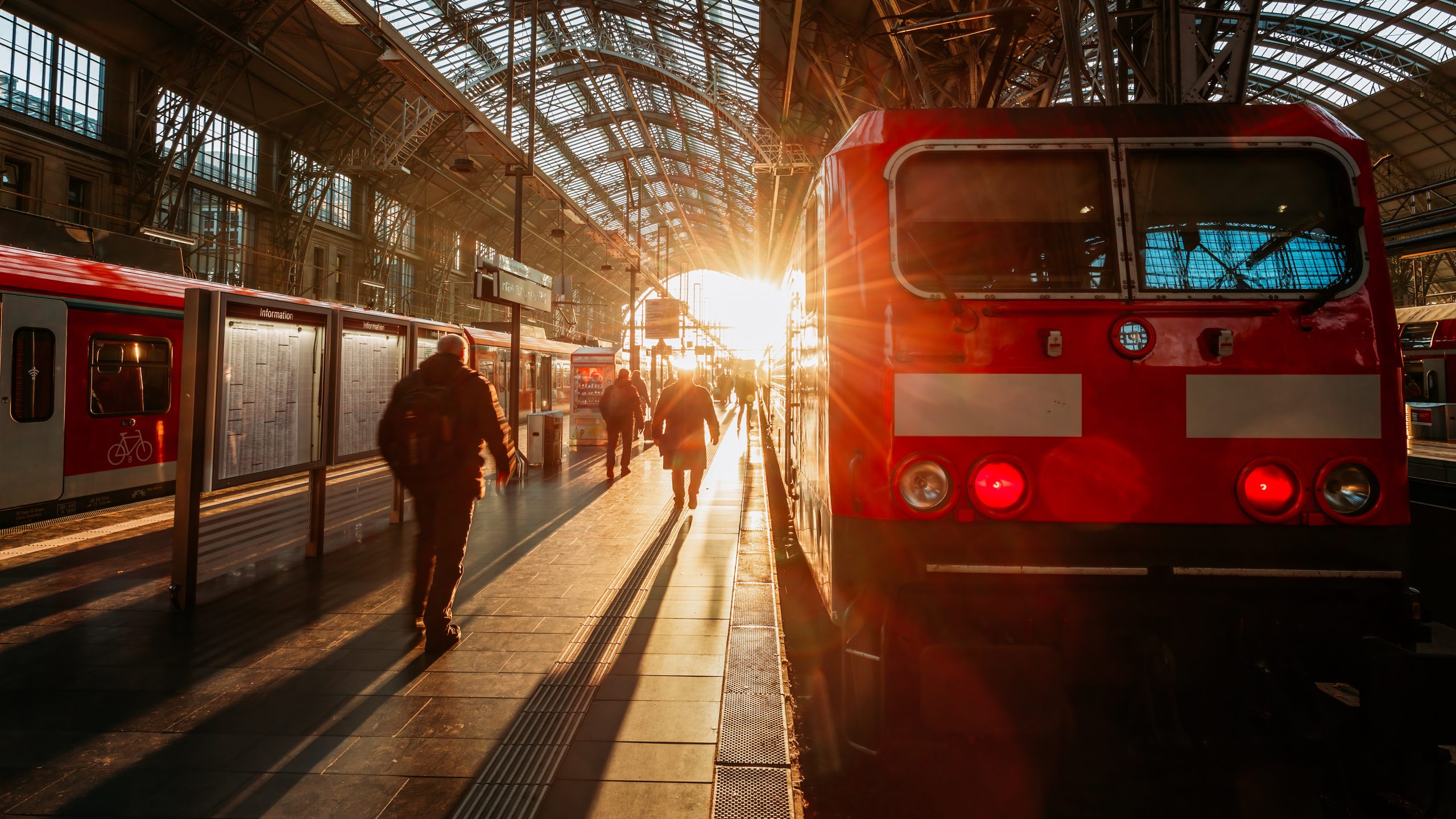 Deutschland Ticket Bahnhof Sonnenuntergang Zug und Personen auf dem Gleis