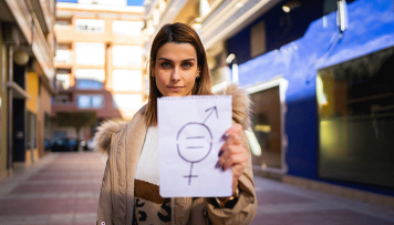 Eine Frau hält ein Papier in die Kamera mit einem Gleichstellungssymbol.