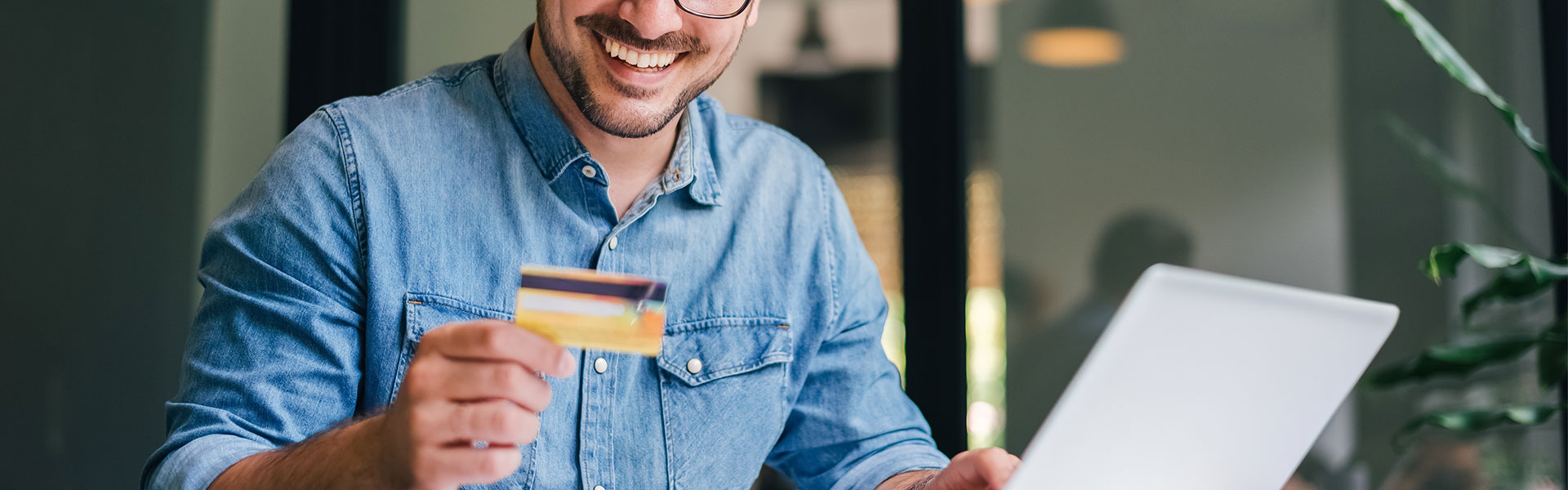 Mit dem Customer Effort Score den Kundenaufwand messen. Ein Man hält eine Kreditkarte in der Hand, während er online etwas bestellt.
