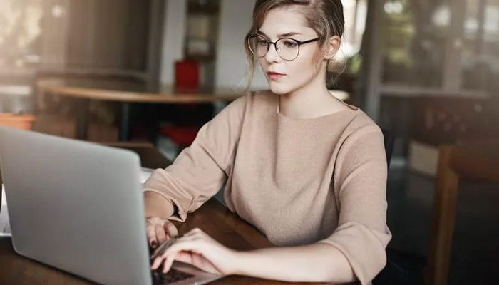 Eine junge Frau gibt am Laptop 360 Grad Feedback.