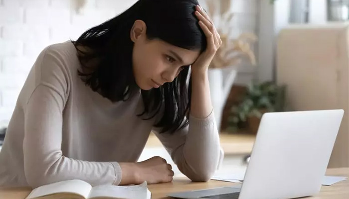 Eine junge Frau sitzt frustriert am Laptop und gibt 360 Grad Feedback.