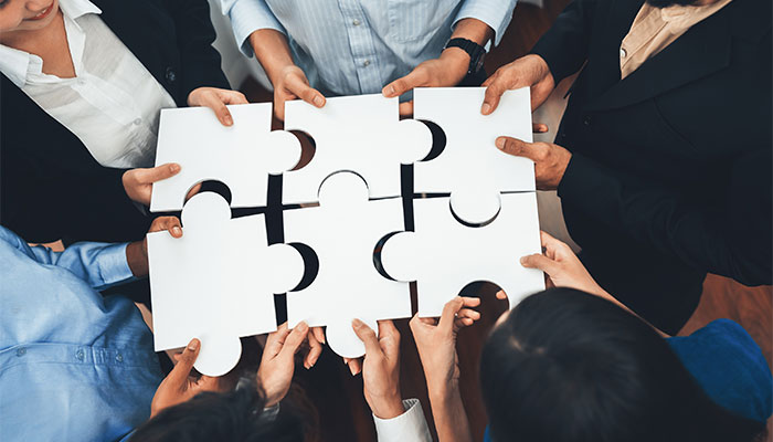 Die Employer Value Proposition hängt von vielen Faktoren ab. Mitarbeitende halten Puzzleteile als Symbol für Zusammenhalt in den Händen.