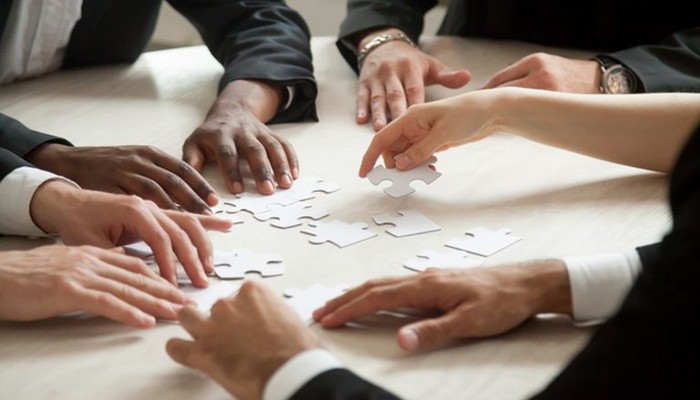 Ein Team fügt im Rahmen einer Führungskräfteentwicklung gemeinsam ein Puzzle zusammen.