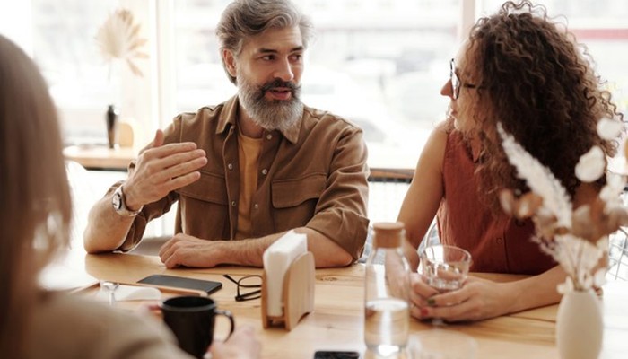 Ein Mann und eine Frau unterhalten sich am Tisch über das Führungskräftefeedback.