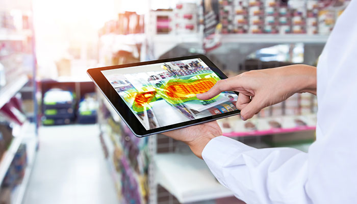 Das Bild zeigt einen Mann, der ein Tablet verwendet, um eine Heatmap Analyse zur Optimierung des Marketingmaterials für einen Supermarkt darzustellen. Diese Analyse zielt darauf ab, die Effektivität des Marketings zu steigern.