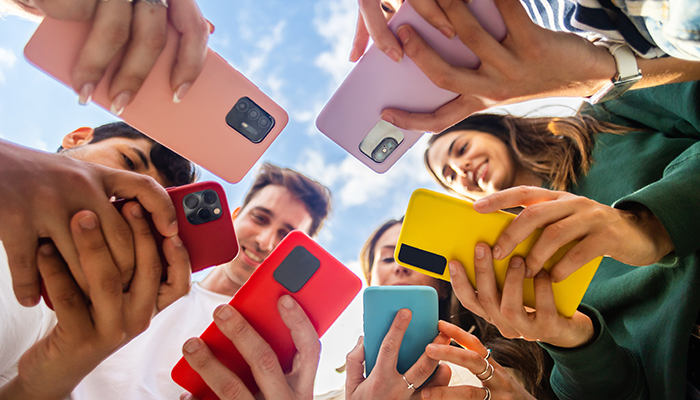 Eine Gruppe junger Menschen füllt im Rahmen der Markenforschung an bunten Smartphones eine Befragung aus.