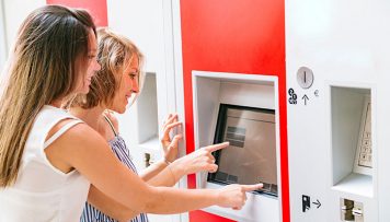 Zwei Frauen stehen vor einem Ticketautomaten und kaufen sich ein Deutschlandticket.