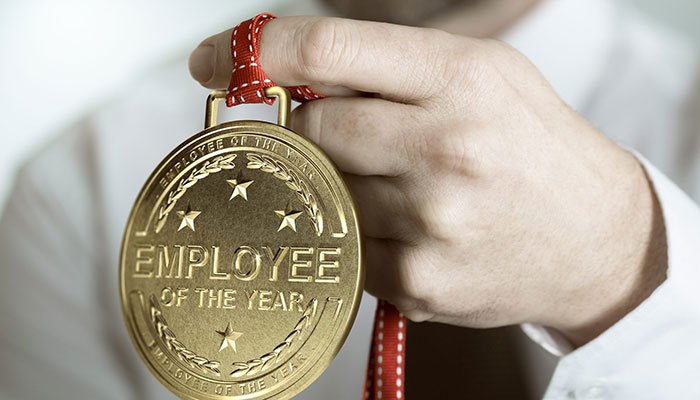 Wahlen im Unternehmen einführen: Ein Mann hält eine Medaille als bester Mitarbeiter des Jahres in der Hand.