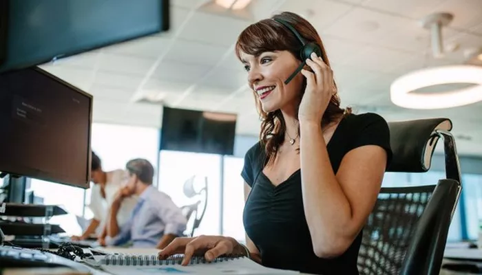 Als Teil der Customer Journey nimmt eine Mitarbeiterin einen Anruf im Call Center entgegen.