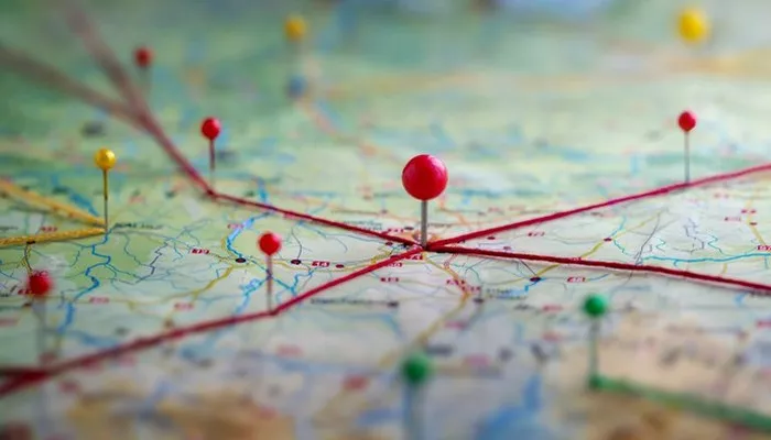 Auf einer Karte werden mit Stecknadeln und roten Fäden eine Customer Journey visualisiert.