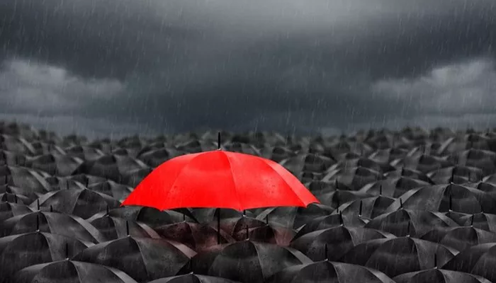 In einem Meer auf schwarzen Regenschirmen sticht ein roter Regenschirm nach oben und symbolisiert eine hohe Markenbekanntheit.